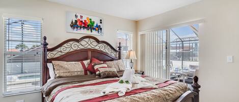 A well-lit bedroom with a large bed, a cityscape artwork on the wall, and a view of the outdoors through the window.