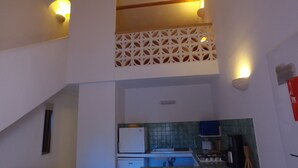A kitchen with a refrigerator, sink, and stove. There is a staircase leading to an upper level with a decorative white lattice. - residence stella d'oro n. 6, f3 a santa giulia (porto vecchio)