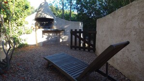 A stone oven, a wooden bench, and a gravel path in a garden setting. - residence stella d'oro n. 6, f3 a santa giulia (porto vecchio)