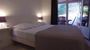 A bedroom with a bed, bedside lamps, and a view of an outdoor area with a table and chairs. - residence stella d'oro n. 6, f3 a santa giulia (porto vecchio)
