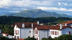 Ein Wohngebiet mit weißen Häusern, roten Fensterläden und einem Berg im Hintergrund.