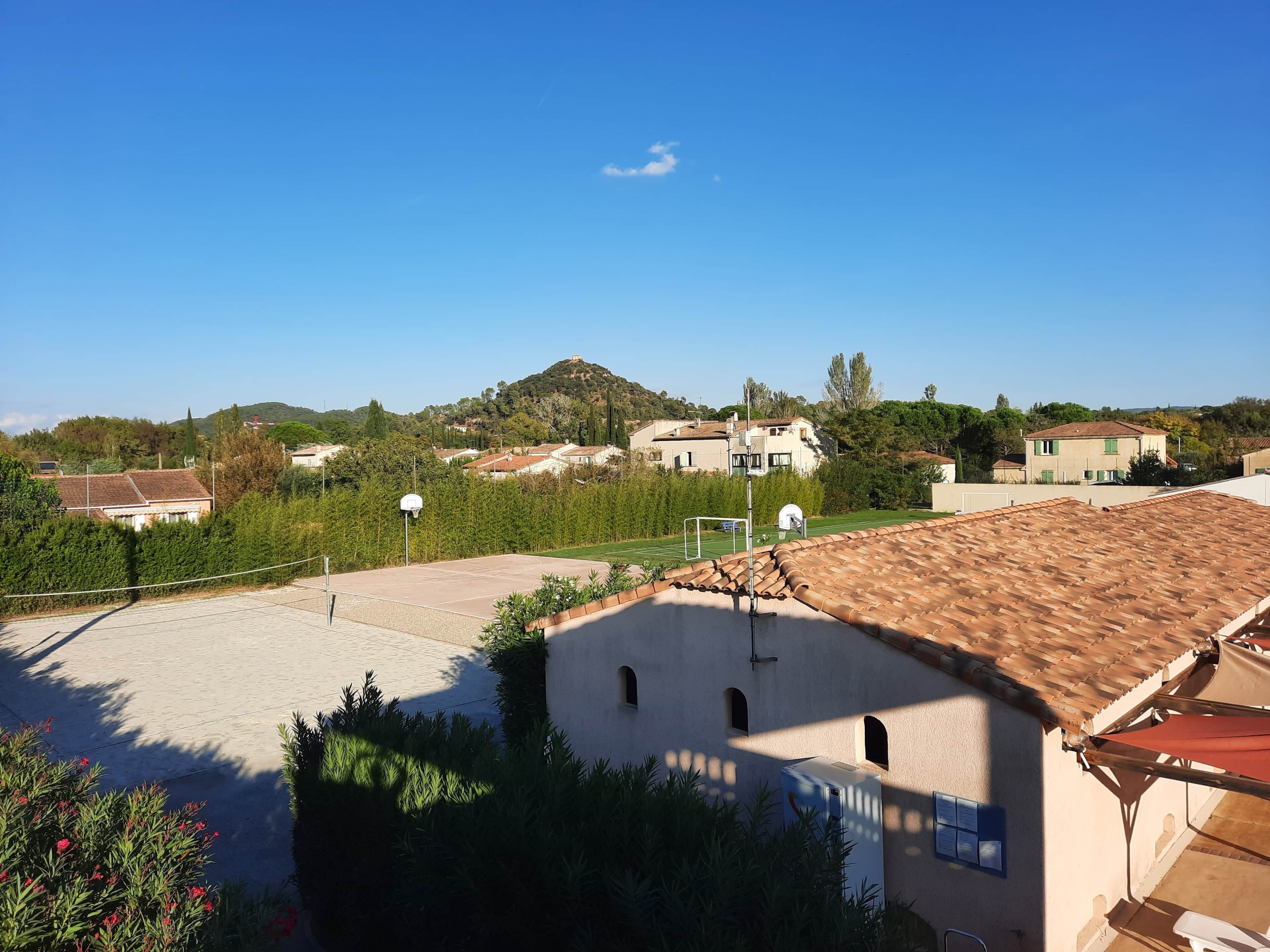 Ein Wohngebiet mit Basketballplatz, einem Haus mit Ziegeldach und einer Hügelkulisse im Hintergrund.