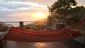 Een hangmat op een betegeld terras met uitzicht op een zonsondergang.