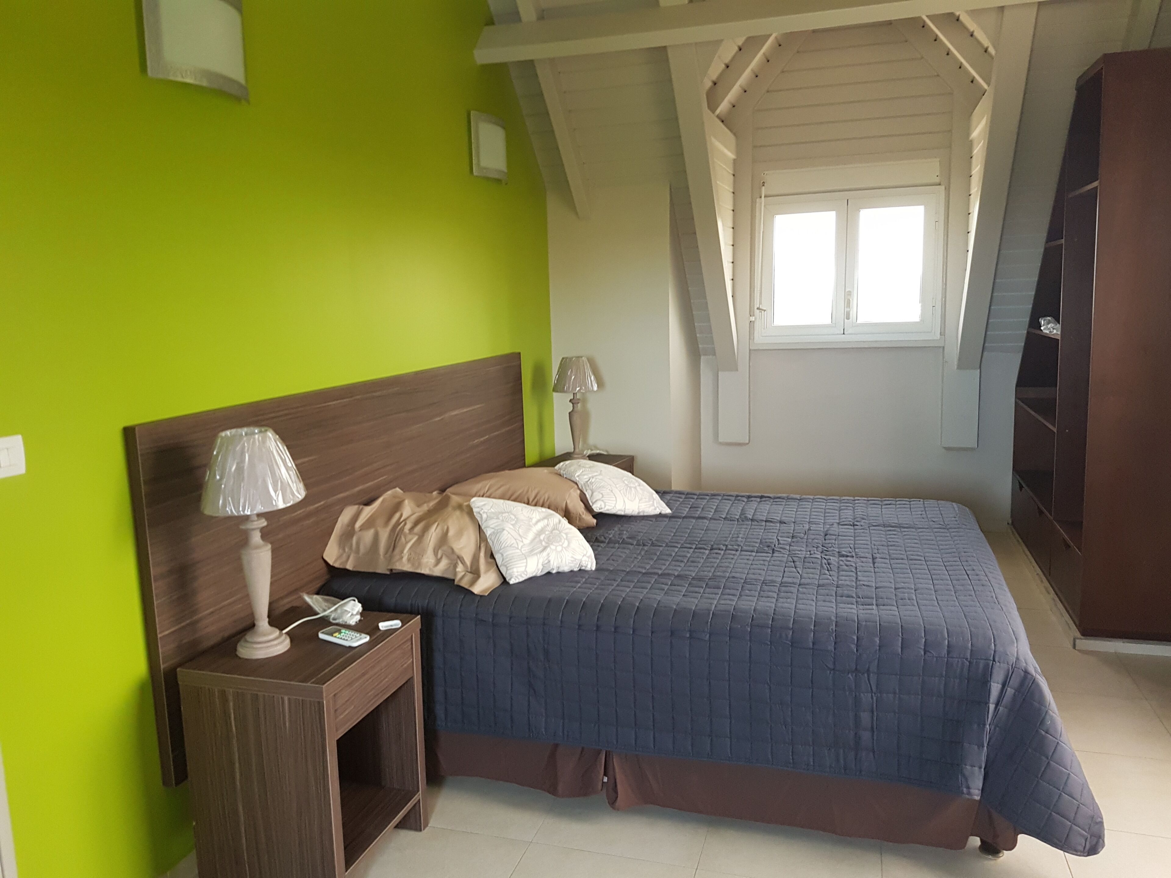 A bedroom with a bed, nightstands, a lamp, and a wardrobe.