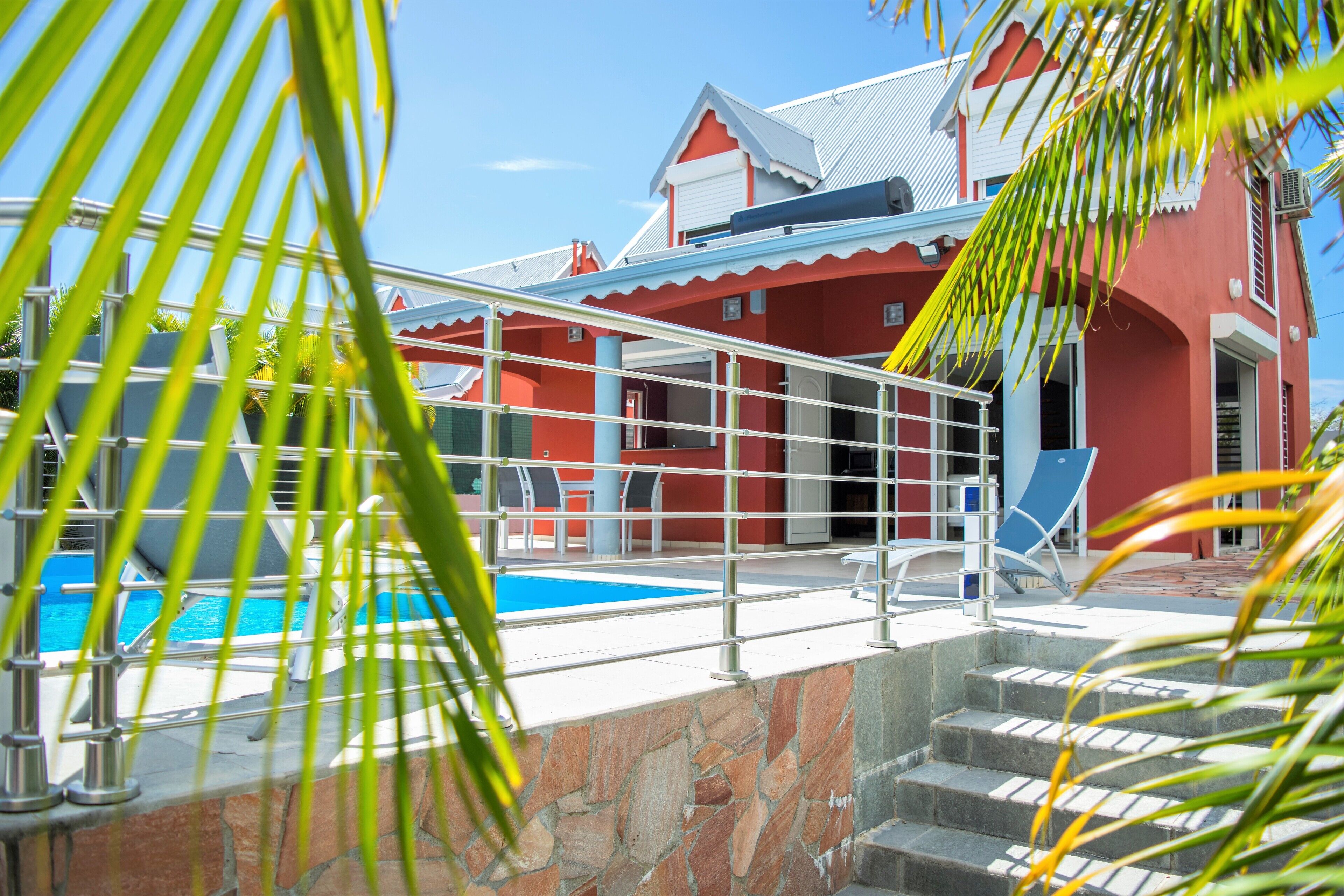 A red building with a pool and stairs leading to a terrace.