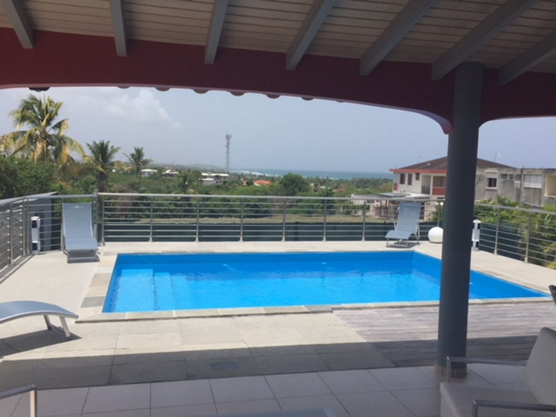 A swimming pool with a covered area, lounge chairs, and a view of the surrounding landscape.