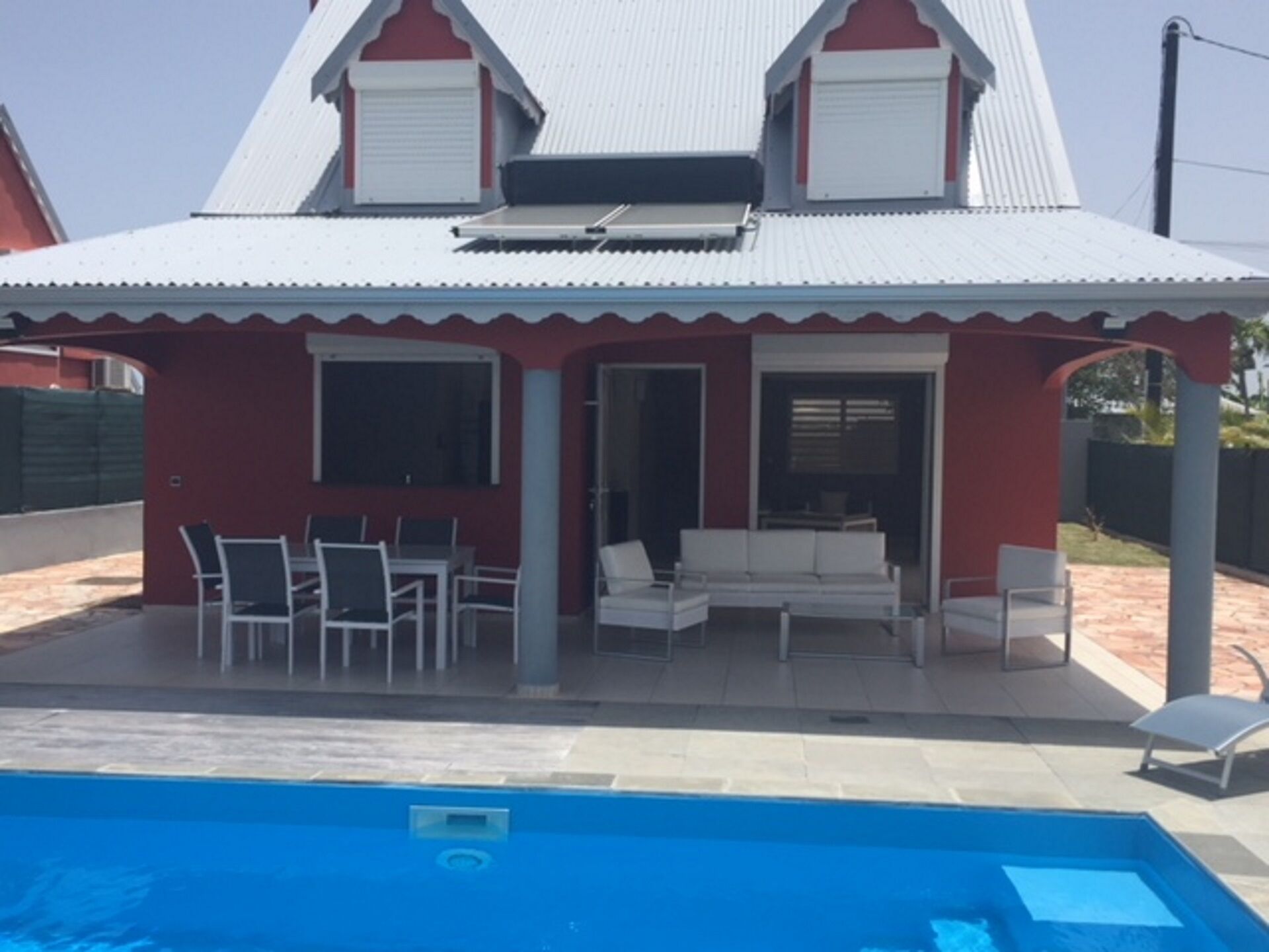 Ett tvåvåningshus med en röd fasad och ett vitt tak. Framför huset finns en swimmingpool.