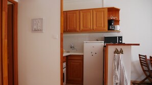 A compact kitchen with wooden cabinets, a white refrigerator, a microwave, and a coffee maker.