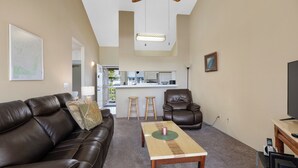 A living room with a brown leather couch, a wooden coffee table, a brown leather chair, and a TV stand. - 🌴Lovely quiet location partial ocean views.This complex requires a 30 day minimum stay.🌴 (Kailua Kona)