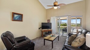 A living room with a leather sofa, a recliner, a coffee table, a TV on a stand, and a ceiling fan. - 🌴Lovely quiet location partial ocean views.This complex requires a 30 day minimum stay.🌴 (Kailua Kona)