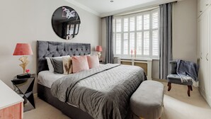 A modern bedroom with a large bed, bedside lamps, a round mirror, and a window with curtains. - Spacious Luxury Flat in Unbeatable Covent Garden Location  (London)