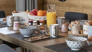 A breakfast table with a fruit basket, a glass of orange juice, and various breakfast items. - Appart 130m², full services 4 *, 4 bedrooms, 4 bathrooms / d, south balcony and 2 parking spaces (Montvalezan)