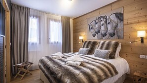 A bedroom with a large bed, wooden walls, a painting of horses, and two bedside lamps. - Appart 130m², full services 4 *, 4 bedrooms, 4 bathrooms / d, south balcony and 2 parking spaces (Montvalezan)