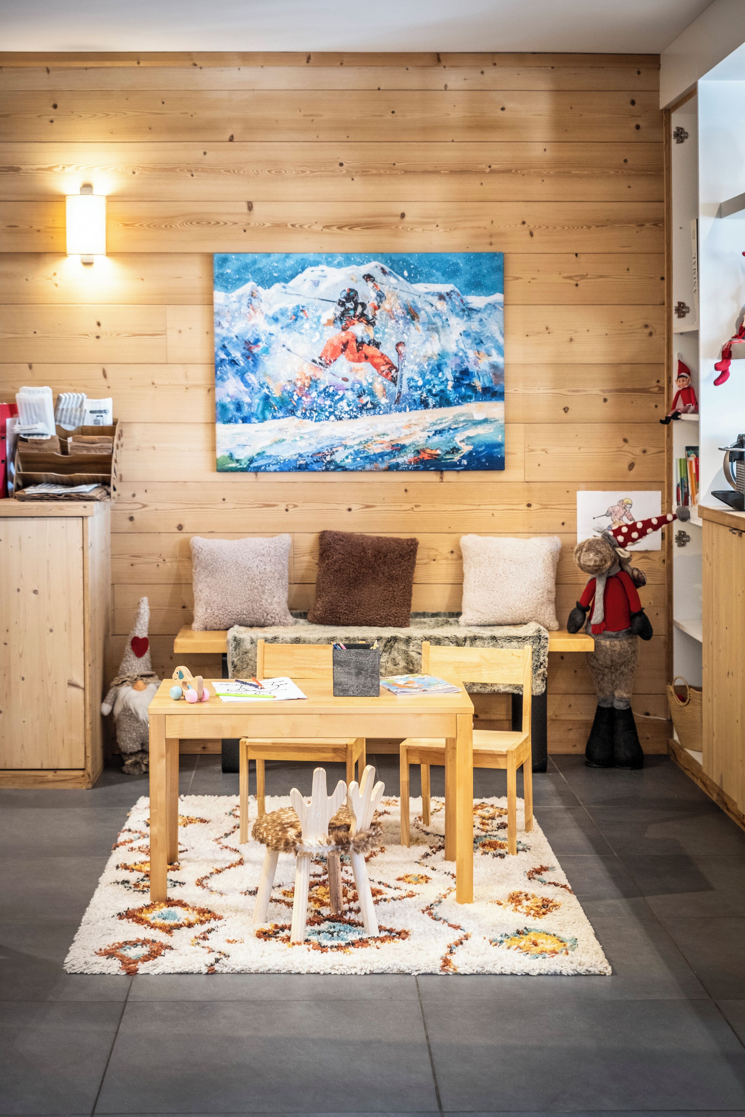 A cozy room with a wooden wall, a painting, a sofa, a table, and a rug.
