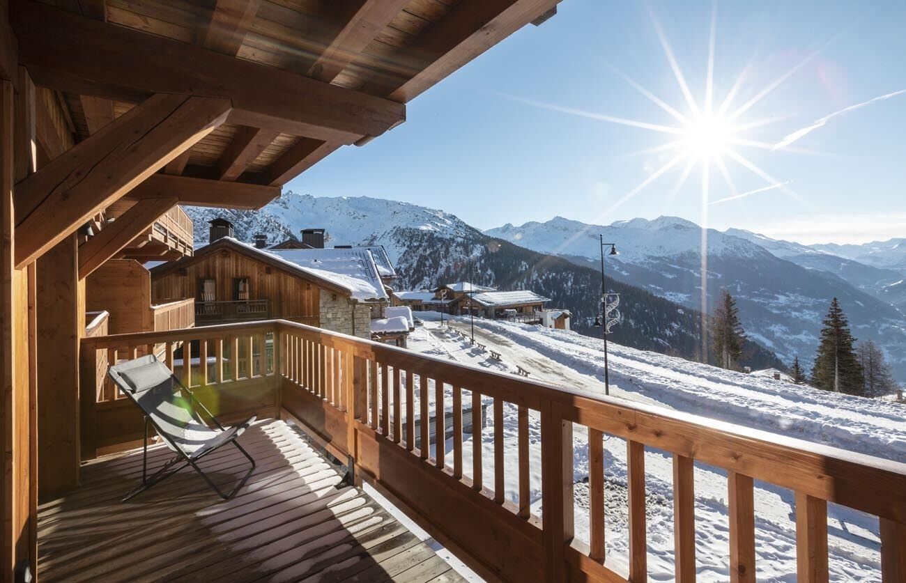Une cabane en bois dotée d’un balcon donnant sur un paysage montagneux enneigé.