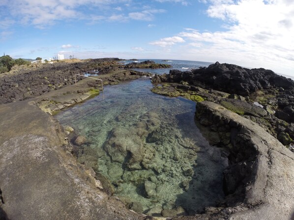 A rocky coastal landscape with clear water and a view of the sea.