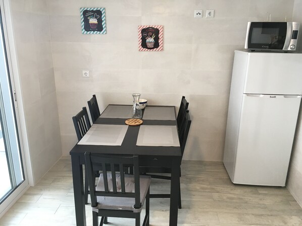A dining area with a table, chairs, a vase, and a microwave on a white cabinet. - 3 bedrooms House facing the Ocean (Lagoa)