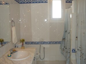 Un baño con lavamanos, espejo, inodoro, ducha y ventana.
