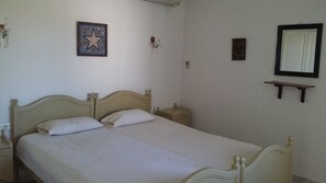 Un dormitorio con una cama individual, una mesita de noche, un estante en la pared y un cuadro enmarcado.