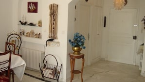Un pasillo con una puerta blanca, un candelabro y una pequeña mesa con un florero.