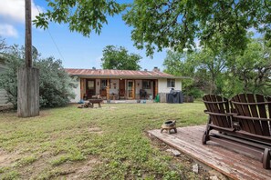 A single-story house with a front porch, a wooden deck, and a grill area. - River Ridge Cabin | Bandera Stay with River Access (Bandera)