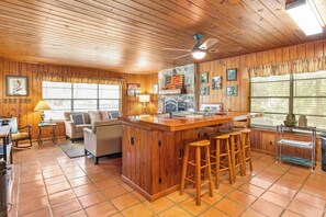 Eine gemütliche Küche mit Holzausbau, einer Bar mit Hockern und einer Wand mit Steinverkleidung.
