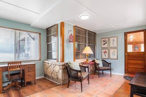 Ein Zimmer mit Schreibtisch, zwei Stühlen, einer Lampe und einem Kamin aus Stein.