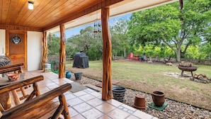 A covered patio with a wooden ceiling, a barbecue grill, and outdoor seating. - River Ridge Cabin | Bandera Stay with River Access (Bandera)