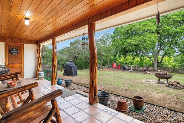 Un patio techado con techo de madera, una parrilla de barbacoa y mobiliario exterior.