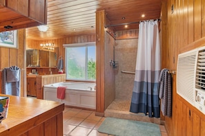 Ein Holzinnenraum mit einem Badezimmer, das eine Badewanne, eine Dusche und ein Fenster mit Blick bietet.