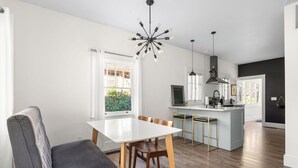 A modern kitchen with a central island, wooden flooring, and pendant lighting. - East End Cottage, History meets Luxury. (Boise)