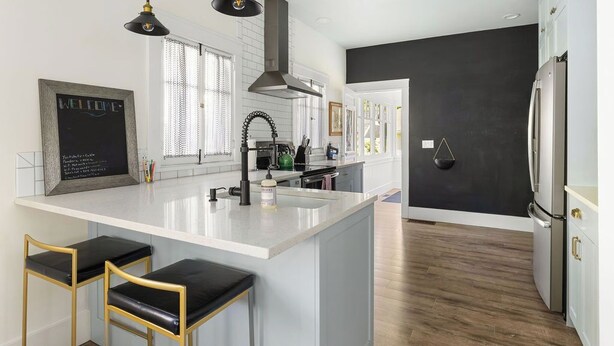 A modern kitchen with a large island, pendant lights, and a chalkboard sign. - East End Cottage, History meets Luxury. (Boise)