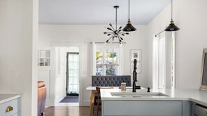 A modern kitchen with a central island, pendant lighting, and a view into the dining area. - East End Cottage, History meets Luxury. (Boise)