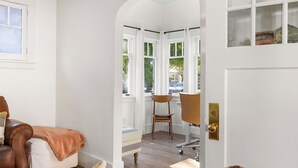 A room with a white door, a brown leather chair, a wooden chair, and a small table. - East End Cottage, History meets Luxury. (Boise)