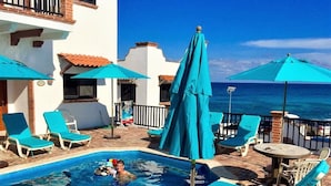 A pool area with lounge chairs and umbrellas, a small pool, and a view of the ocean. - Ocean View Villa "Saltillo" with a/c and 2 pools, 5 min stroll to beach (Isla Mujeres)