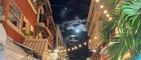 A street lined with buildings, outdoor seating, and string lights.