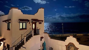 A coastal building with a staircase leading to a balcony, a clock, and a view of the sea. - Ocean View Villa "Saltillo" with a/c and 2 pools, 5 min stroll to beach (Isla Mujeres)