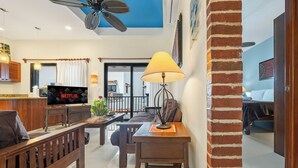 A modern living room with a TV, wooden furniture, a ceiling fan, and a brick column. - Ocean View Villa "Saltillo" with a/c and 2 pools, 5 min stroll to beach (Isla Mujeres)