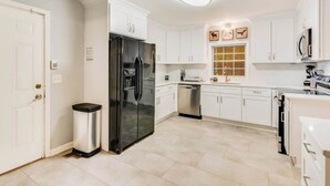 A modern kitchen with white cabinetry, a stainless steel refrigerator, and a dishwasher.