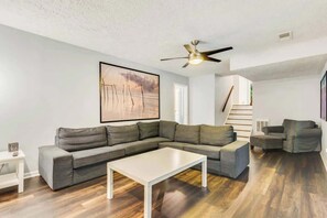 A modern living room with a sectional sofa, a coffee table, and a ceiling fan.