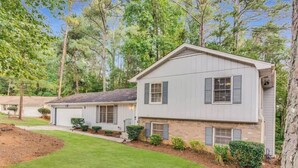 A two-story house with a garage, surrounded by a well-maintained lawn and trees.