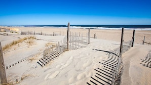 A sandy beach with a wooden fence and a clear blue sky. - Oceanfront Dog Friendly Home with Home Theater, Hot Tub, Grill (Waves)