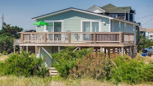 A two-story house with a wooden deck and a green umbrella. - Oceanfront Dog Friendly Home with Home Theater, Hot Tub, Grill (Waves)