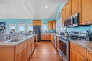 A kitchen with wooden cabinets, granite countertops, stainless steel appliances, and a view of the outdoors.