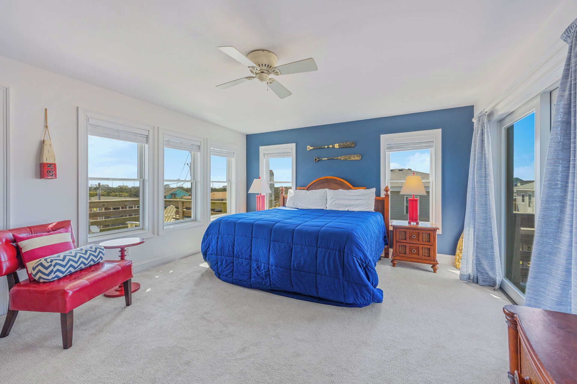A bedroom with a bed, a chair, a nightstand, a lamp, and a ceiling fan.