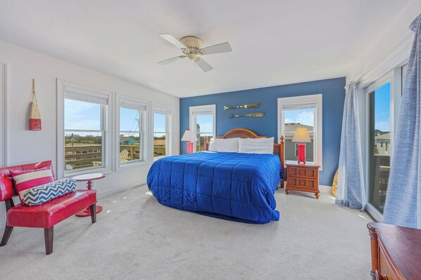 A bedroom with a bed, a chair, a nightstand, a lamp, and a ceiling fan.