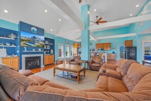 A spacious living room with a fireplace, leather sofas, and a dining area. - Oceanview Dog Friendly Home w/ Private Pool, Hot Tub, Elevator, and Game Room (Rodanthe)