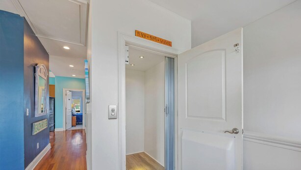 Ein Flur mit einer Tür zu einem Zimmer, einem Schild mit der Aufschrift 'BEACH BUMS WELCOME' und einer blauen Wand mit Spiegel und Schild, das 'EACH HOUSE' sagt.