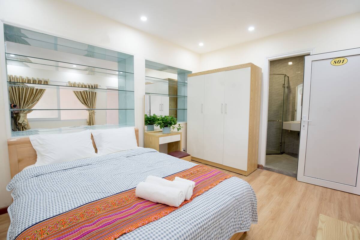 Una camera d'albergo con un letto, un armadio, un bagno e una scrivania con una pianta.