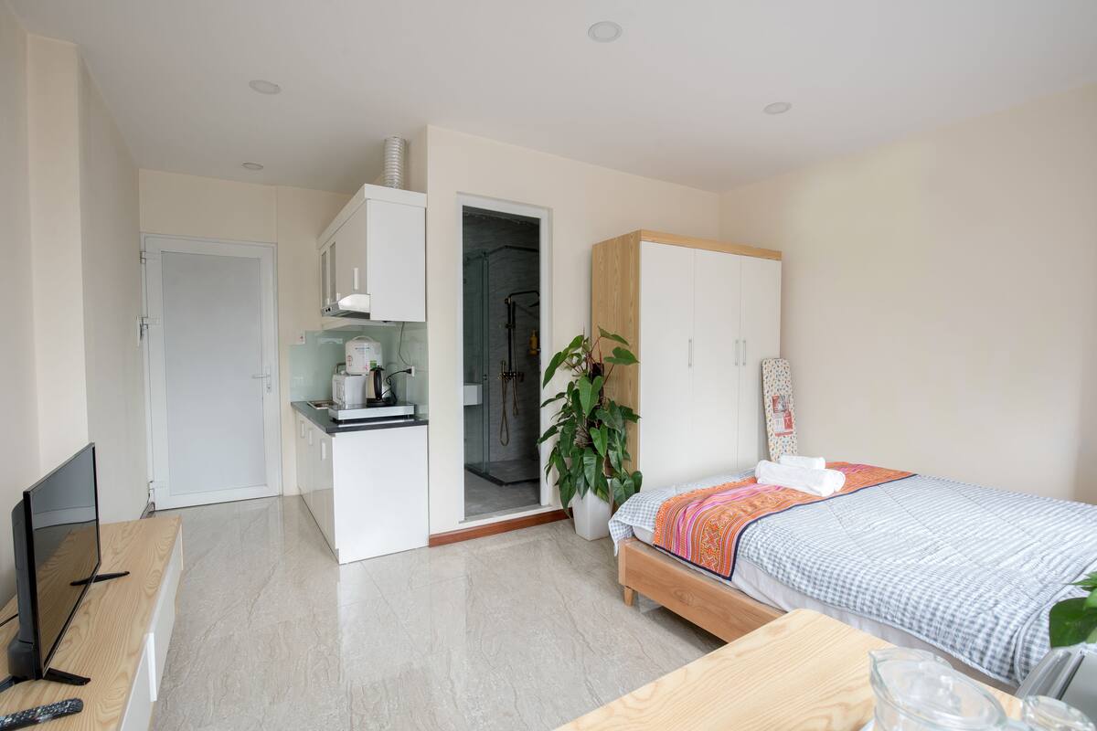 Camera d'albergo moderna con un letto, una scrivania con un computer, una TV e un bagno visibile attraverso una porta aperta.